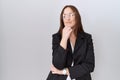 Beautiful brunette woman wearing business jacket and glasses looking confident at the camera smiling with crossed arms and hand Royalty Free Stock Photo