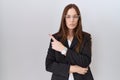 Beautiful brunette woman wearing business jacket and glasses pointing with hand finger to the side showing advertisement, serious Royalty Free Stock Photo