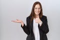 Beautiful brunette woman wearing business jacket and glasses showing palm hand and doing ok gesture with thumbs up, smiling happy Royalty Free Stock Photo