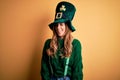 Beautiful brunette woman wearing green hat with clover celebrating saint patricks day winking looking at the camera with sexy