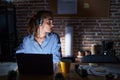 Beautiful brunette woman working at the office at night looking to side, relax profile pose with natural face with confident smile Royalty Free Stock Photo