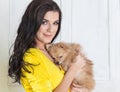 Beautiful brunette woman in yellow dress with small dog in hands Royalty Free Stock Photo