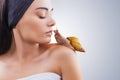 Beautiful young woman kissing giant Achatina snail on light background