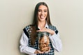 Beautiful brunette young woman holding jar of chocolate chips cookies sticking tongue out happy with funny expression Royalty Free Stock Photo