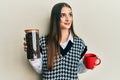 Beautiful brunette young woman holding jar with coffee beans and drinking coffee cup smiling looking to the side and staring away Royalty Free Stock Photo