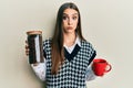 Beautiful brunette young woman holding jar with coffee beans and drinking coffee cup puffing cheeks with funny face Royalty Free Stock Photo