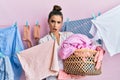 Beautiful brunette young woman holding laundry basket in shock face, looking skeptical and sarcastic, surprised with open mouth Royalty Free Stock Photo