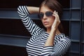 Beautiful brunette young woman in nice striped dress, sunglasses. Posing on urban background. Fashion Photo Royalty Free Stock Photo