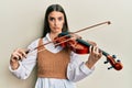 Beautiful brunette young woman playing violin depressed and worry for distress, crying angry and afraid Royalty Free Stock Photo