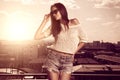 Beautiful brunette young woman posing above sunset city background Royalty Free Stock Photo