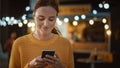 Beautiful Brunette Young Woman is Using a Smartphone while Standing Outdoors in the Evening. She Royalty Free Stock Photo