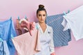 Beautiful brunette young woman washing clothes at clothesline looking unhappy and angry showing rejection and negative with thumbs Royalty Free Stock Photo