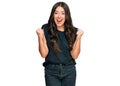 Beautiful brunette young woman wearing black shirt celebrating surprised and amazed for success with arms raised and open eyes Royalty Free Stock Photo
