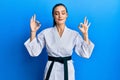 Beautiful brunette young woman wearing karate fighter uniform with black belt relax and smiling with eyes closed doing meditation Royalty Free Stock Photo