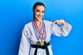 Beautiful brunette young woman wearing karate fighter uniform and medals pointing finger to one self smiling happy and proud