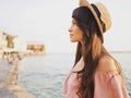 Stylish brunette woman enjoying sunrise on seafront