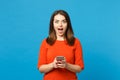 Beautiful brunette young woman wearing red orange dress messaging using mobile phone isolated over trendy blue wall Royalty Free Stock Photo