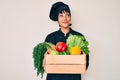 Beautiful brunettte woman chef holding fresh veggetables smiling looking to the side and staring away thinking Royalty Free Stock Photo