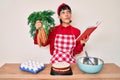 Beautiful brunettte woman cooking carrot cake reading recipes book smiling looking to the side and staring away thinking Royalty Free Stock Photo