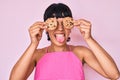Beautiful brunettte woman holding chocolate chips cookies on eyes sticking tongue out happy with funny expression Royalty Free Stock Photo