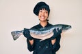 Beautiful brunettte woman professional chef holding fresh salmon fish smiling looking to the side and staring away thinking Royalty Free Stock Photo