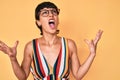 Beautiful brunettte woman wearing casual clothes and glasses crazy and mad shouting and yelling with aggressive expression and Royalty Free Stock Photo