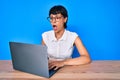Beautiful brunettte woman working using computer laptop scared and amazed with open mouth for surprise, disbelief face Royalty Free Stock Photo