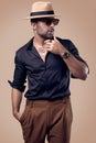 Beautiful brutal tanned hipster man in a black shirt, hat and glasses Royalty Free Stock Photo