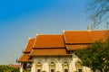 Beautiful Buddhist church, ubosot sanctuary hall with its expansive orange tiles roof under blue sky. Orange and red roof tiles at Royalty Free Stock Photo