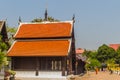 Beautiful Buddhist church, ubosot sanctuary hall with its expansive orange tiles roof under blue sky. Orange and red roof tiles at Royalty Free Stock Photo