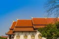 Beautiful Buddhist church, ubosot sanctuary hall with its expansive orange tiles roof under blue sky. Orange and red roof tiles at Royalty Free Stock Photo