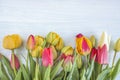 Beautiful bunch of fresh multicolored tulips with waterdrops on light wooden background