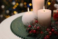 Beautiful burning candles and Christmas decor on white table against festive lights. Space for text Royalty Free Stock Photo