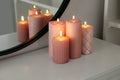 Beautiful burning candles on white console table near mirror indoors Royalty Free Stock Photo