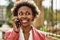 Beautiful business african american woman with afro hair smiling happy and confident outdoors at the city having a conversation Royalty Free Stock Photo