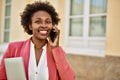 Beautiful business african american woman with afro hair smiling happy and confident outdoors at the city having a conversation Royalty Free Stock Photo