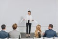 beautiful business coach standing on stage and gesturing during training