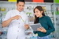 beautiful business girl using a tablet checking stock of accessories products with a male shop clerk carrying product
