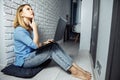 Beautiful business lady in casual is using a laptop and smiling while sitting on the floor at home and working Royalty Free Stock Photo