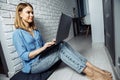 Beautiful business lady in casual is using a laptop and smiling while sitting on the floor at home and working Royalty Free Stock Photo