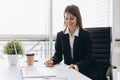 Beautiful business lady is looking at laptop and smiling while working in office. Concentrated on work