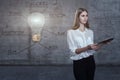 Beautiful business woman against a concrete wall with sketch drawn on it and bright lightbulb