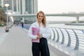 A beautiful business woman with a folder of documents in her hands outdoors. City portrait, business portrait Royalty Free Stock Photo