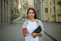 Beautiful business woman is going to work with coffee walking near office buildings. Portrait of a successful business woman holdi Royalty Free Stock Photo