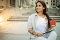 Beautiful business woman is going to work with coffee walking near office buildings. Portrait of a successful business woman holdi Royalty Free Stock Photo