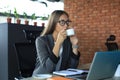 Beautiful business woman is holding coffee cup and smiling while sitting at her working place Royalty Free Stock Photo