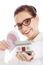 Beautiful business woman holding money and small house. Royalty Free Stock Photo