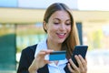 Beautiful business woman holds smart phone and credit card making shopping online outdoor office on break time. People and online Royalty Free Stock Photo