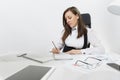 Beautiful business woman in suit and glasses working at computer with documents in light office Royalty Free Stock Photo