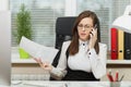 Beautiful business woman in suit and glasses working at computer with documents in light office Royalty Free Stock Photo